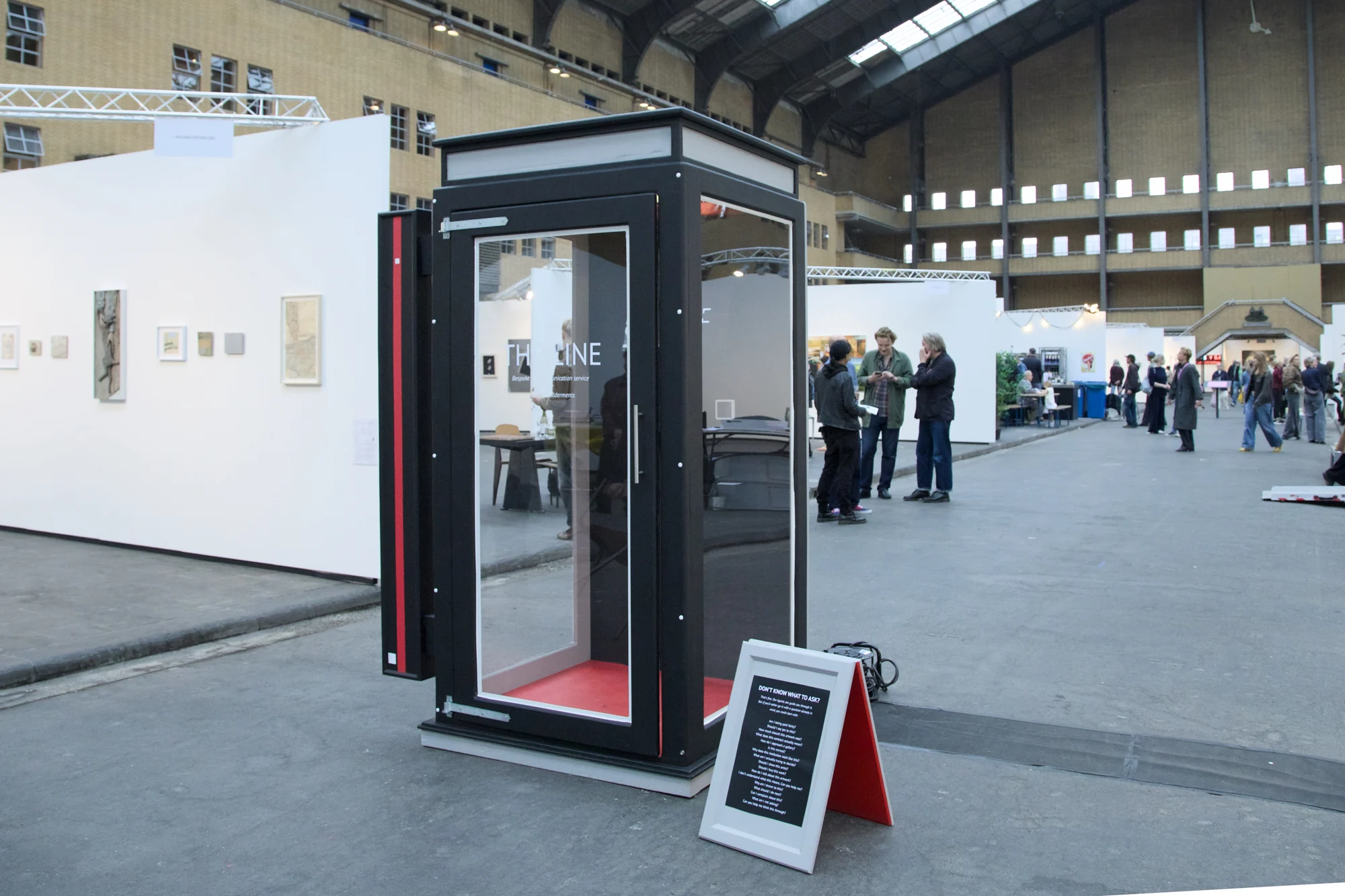 The Line’s glass-fronted telephone booth on the art fair floor.