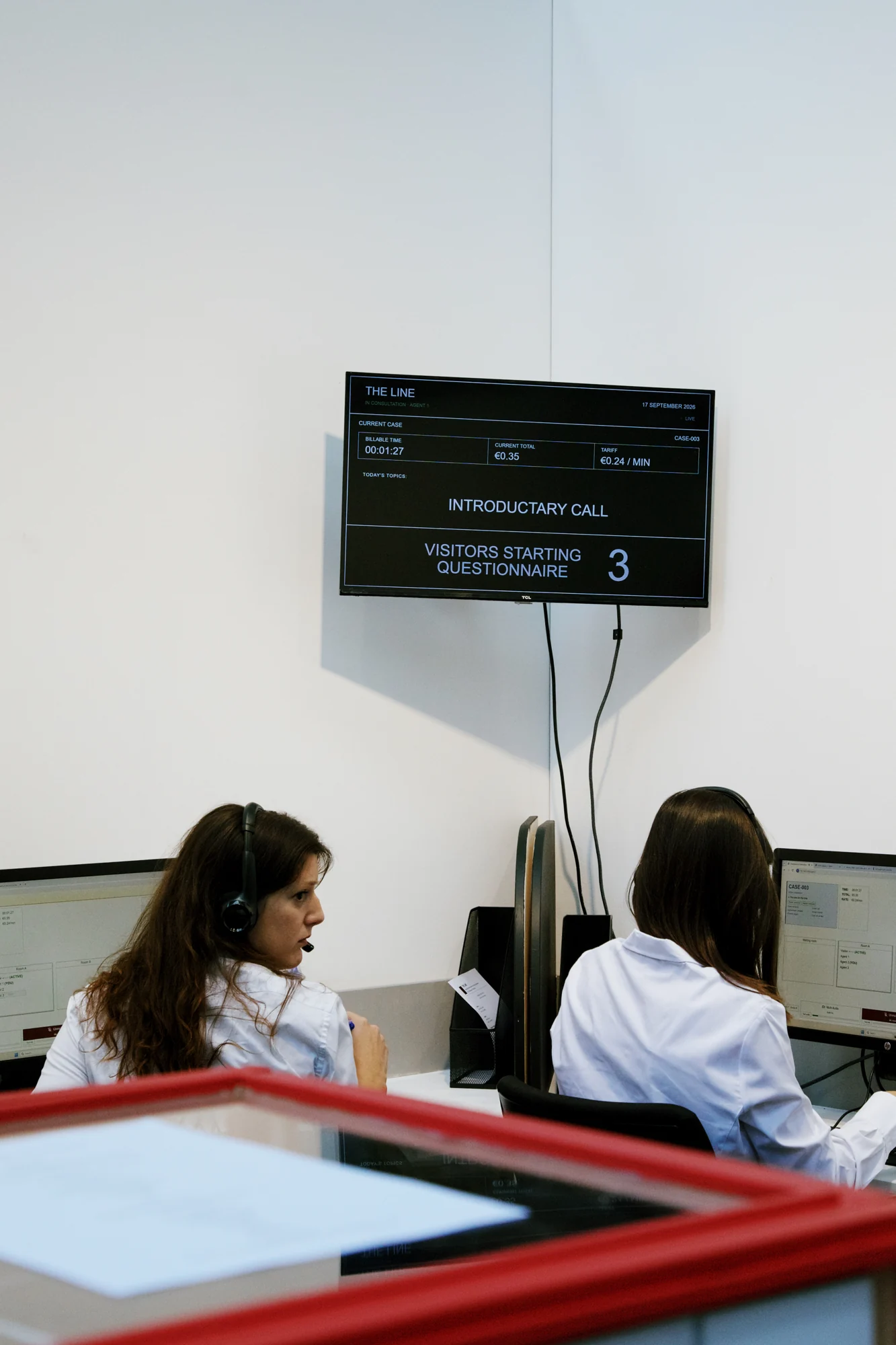 Agents working at their stations beneath the call centre’s statistics screen.